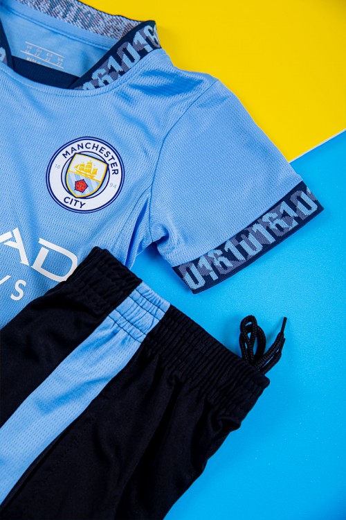 طقم ولادي رياضي قطعتين تيشيرت مانشستر سيتي بأكمام قصيرة و بنطلون طويل لون أسود مخطط باللون السماوي من الجانبين بزم من الخصر و الأسفل