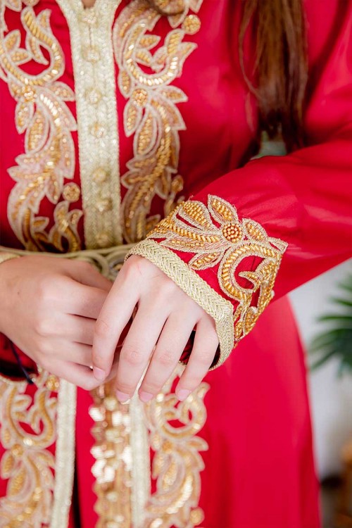 جلابية نسائية لون أحمر مزينة بتطريز ذهبي و بأزرار من الأمام و بحزام في الخصر مزين بفصوص من الاكسسوار