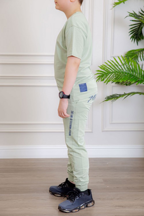 ترنج ولادي قطعتين لون تفاحي تيشيرت بكتابات من الأمام و الخلف و بنطلون بجيوب من الجانبين و الخلف و برباط في الخصر