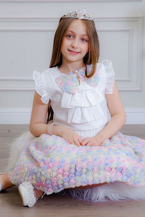 طقم تيور بناتي قطعتين بلوزة بلون أبيض مزينة بفيونكة ملونة من الأمام بدون أكمام و تـنورة ملونة