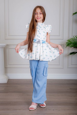 بدلة بناتي قطعتين بلوزة لون أبيض بياقة عالية بدون أكمام مزينة بورود سماوية و أزرار من الأمام و حزام في الخصر مع بنطلون طويل لون سماوي بجيوب من الجانبين