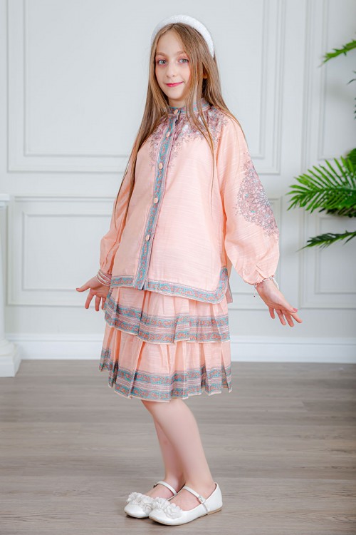 طقم تيور بناتي قطعتين لون خربزي بلوزة بياقة عالية و أزرار من الأمام ذو أكمام طويلة و تـنورة مزين بزخارف ملونة من الأطراف و الأكمام