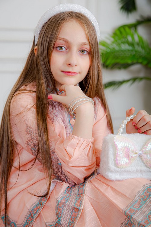 طقم تيور بناتي قطعتين لون خربزي بلوزة بياقة عالية و أزرار من الأمام ذو أكمام طويلة و تـنورة مزين بزخارف ملونة من الأطراف و الأكمام