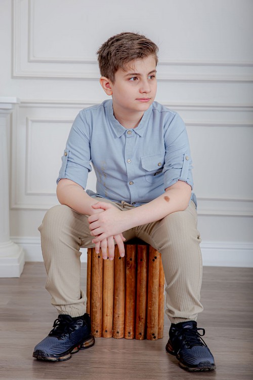 بدلة ولادي قطعتين قميص لون سماوي  بأزرار و جيب و كتابات من الأمام و بنطلون لون بيج بجيوب من الجانبين و الخلف و برباط في الخصر