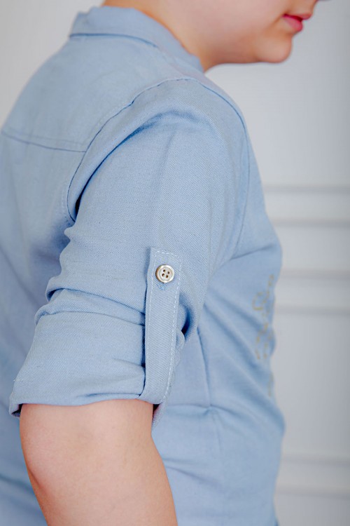 بدلة ولادي قطعتين قميص لون سماوي  بأزرار و جيب و كتابات من الأمام و بنطلون لون بيج بجيوب من الجانبين و الخلف و برباط في الخصر