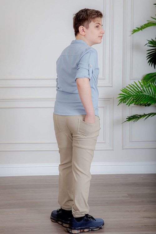 بدلة ولادي قطعتين قميص لون سماوي  بأزرار و جيب و كتابات من الأمام و بنطلون لون بيج بجيوب من الجانبين و الخلف و برباط في الخصر