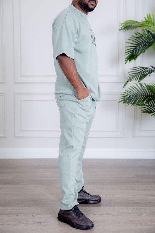 طقم رجالي قطعتين لون تيفاني فاتح تيشيرت بكتابات و طبعات مع بنطلون طويل بجيوب من الجانبين و الخلف و برباط في الخصر