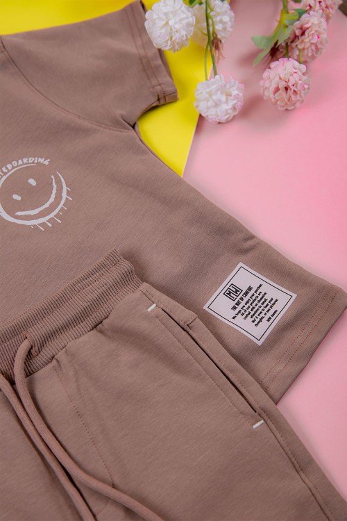 ترنج ولادي قطعتين لون لحمي تيشيرت برسومات و كتابات من الأمام و شورت برباط في الخصر و جيوب من الجانبين و الخلف