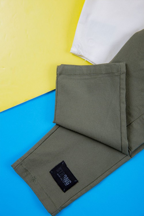 طقم ولادي قطعتين قميص أبيض بكتابات و جيب و أزرار من الأمام و بنطلون لون زيتي برباط في الخصر و جيوب من الجانبين