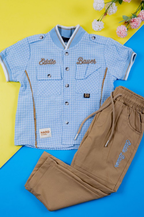 طقم ولادي قطعتين قميص سماوي مربعات بكتابات و جيبوب و أزرار من الأمام و بنطلون لون بيج غامق برباط في الخصر و جيوب من الجانبين