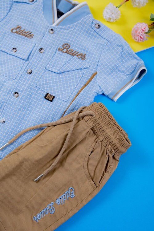 طقم ولادي قطعتين قميص سماوي مربعات بكتابات و جيبوب و أزرار من الأمام و بنطلون لون بيج غامق برباط في الخصر و جيوب من الجانبين