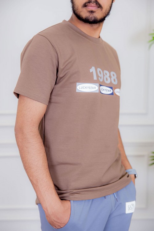 تيشيرت رجالي لون بني فاتح  مزين بكتابات ملونة من الأمام