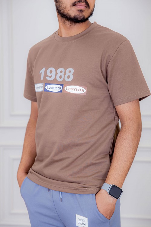 تيشيرت رجالي لون بني فاتح  مزين بكتابات ملونة من الأمام