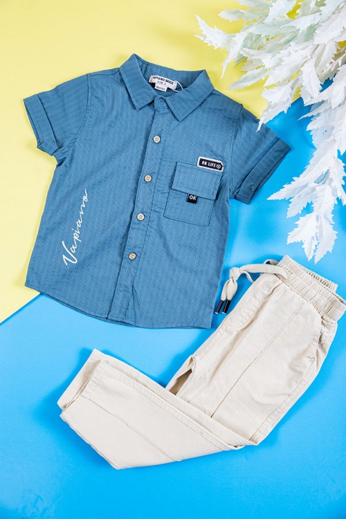 طقم ولادي قطعتين قميص لون سماوي بكتابات و طبعات و أزرار و جيب من الأمام و بنطلون طويل لون بيج فاتح برباط في الخصر و جيوب من الجانبين و الخلف