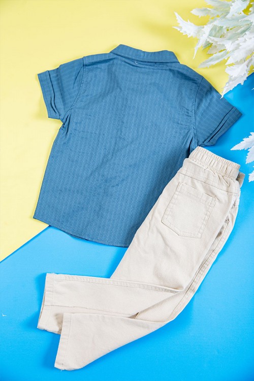 طقم ولادي قطعتين قميص لون سماوي بكتابات و طبعات و أزرار و جيب من الأمام و بنطلون طويل لون بيج فاتح برباط في الخصر و جيوب من الجانبين و الخلف