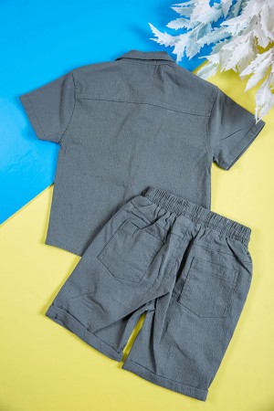 طقم ولادي قطعتين لون رصاصي قميص بكتابات و طبعات وجيوب وازرار من الأمام و شورت برباط في الخصر و جيوب من الجانبين و الخلف