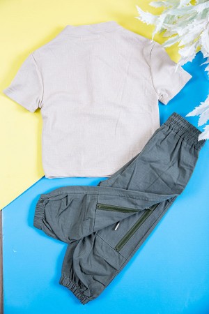 طقم ولادي قطعتين بلوزة لون بيج فاتح بكتابات و طبعات و أزرار و جيب من الأمام و بنطلون طويل لون رصاصي برباط في الخصر و جيوب و سحاب من الجانبين 