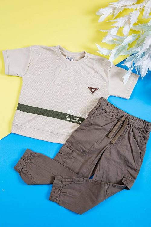 طقم ولادي قطعتين تيشيرت لون بيج فاتح بكتابات و طبعات من الأمام و بنطلون طويل لون بني بجيوب من الجانبين