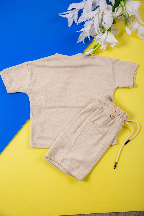 طقم ولادي قطعتين لون بيج تيشيرت بكتابات و طبعات من الأمام و شورت برباط في الخصر و جيوب من الجانبين
