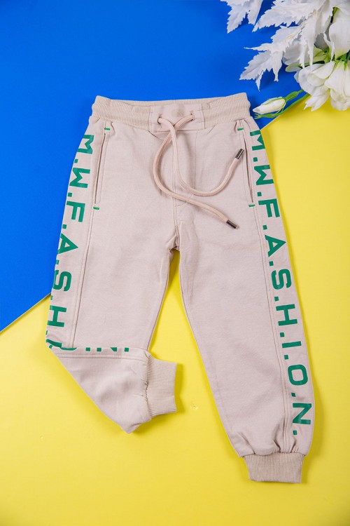 طقم ولادي قطعتين لون بيج تيشيرت بكتابات باللون الأخضر و طبعات و بنطلون طويل برباط في الخصر و جيوب من الجانبين وزم في الأسفل