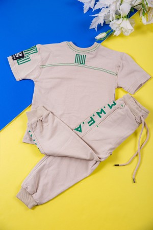 طقم ولادي قطعتين لون بيج تيشيرت بكتابات باللون الأخضر و طبعات و بنطلون طويل برباط في الخصر و جيوب من الجانبين وزم في الأسفل