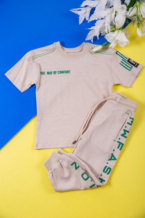 طقم ولادي قطعتين لون بيج تيشيرت بكتابات باللون الأخضر و طبعات و بنطلون طويل برباط في الخصر و جيوب من الجانبين وزم في الأسفل