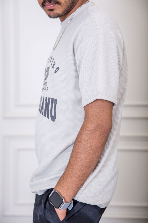 تيشيرت رجالي لون رمادي فاتح بياقة دائرية مزين بكتابات و رسومات من الأمام