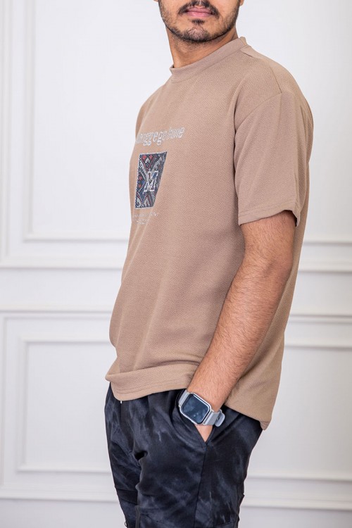 تيشيرت رجالي لون بيج غامق بياقة دائرية مزين بكتابات و طبعات من الأمام
