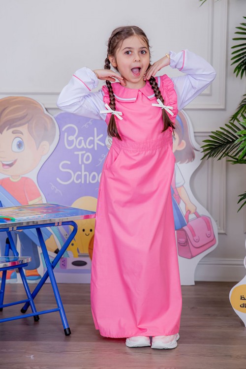 مريول بناتي مدرسي لون وردي مع قميص أبيض متصل و بأكتاف كرانيش و جيوب من الجانبين و رباط في الخصر