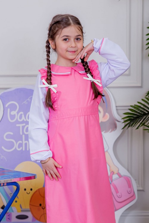 مريول بناتي مدرسي لون وردي مع قميص أبيض متصل و بأكتاف كرانيش و جيوب من الجانبين و رباط في الخصر