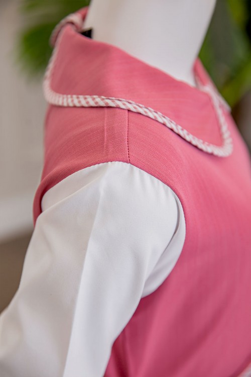 مريول بناتي مدرسي لون وردي مع قميص أبيض متصل بياقة مطوية و جيوب من الأمام و سحاب و رباط في الخلف