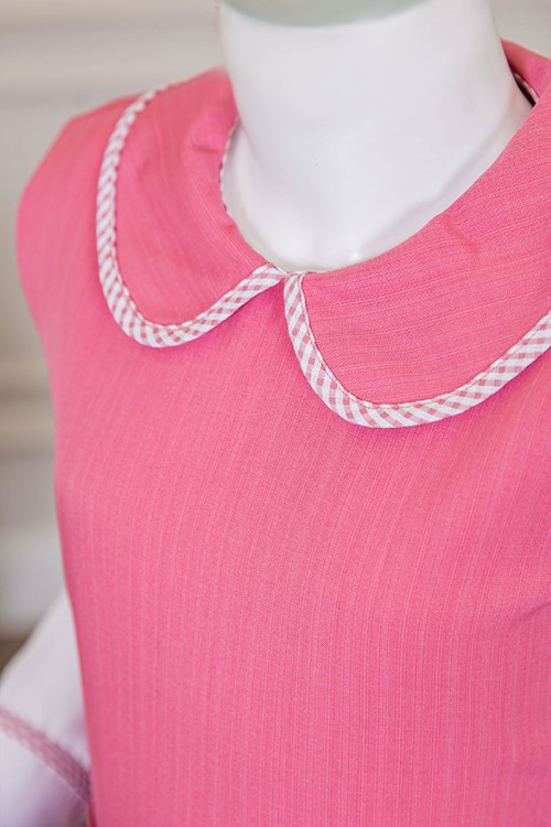 مريول بناتي مدرسي لون وردي مع قميص أبيض متصل بياقة مطوية و جيوب من الأمام و سحاب و رباط في الخلف