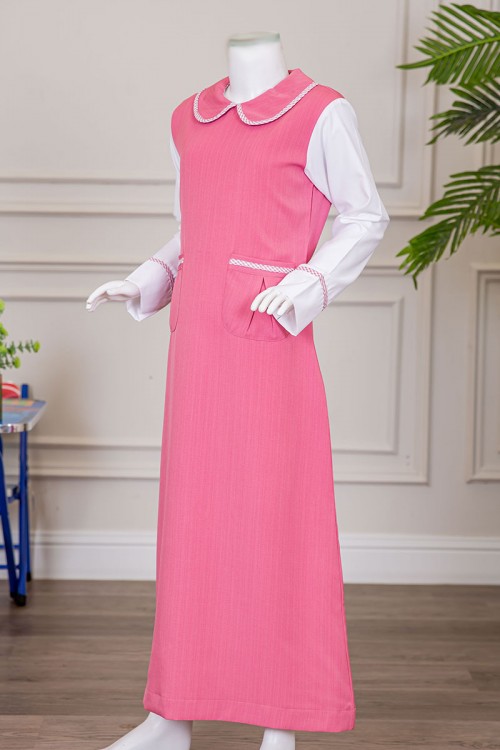 مريول بناتي مدرسي لون وردي مع قميص أبيض متصل بياقة مطوية و جيوب من الأمام و سحاب و رباط في الخلف