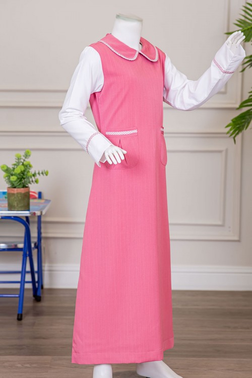 مريول بناتي مدرسي لون وردي مع قميص أبيض متصل بياقة مطوية و جيوب من الأمام و سحاب و رباط في الخلف