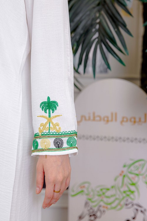 جلابية نسائية لليوم الوطني لون أبيض مزينة بتطريز شعار المملكة العربية السعودية سيفين و نخلة و بياقة مربعة