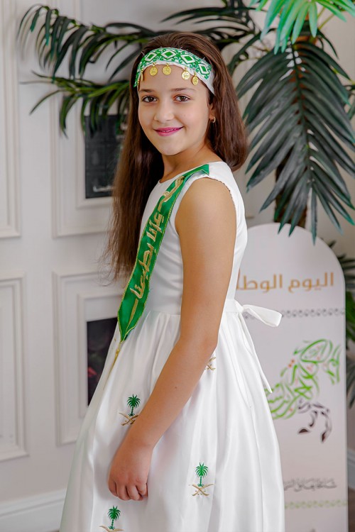 فستان بناتي لون أبيض لليوم الوطني مع وشاح أخضر مزين بتطريز ذهبي بياقة دائرية بدون أكمام و رباط في الخصر