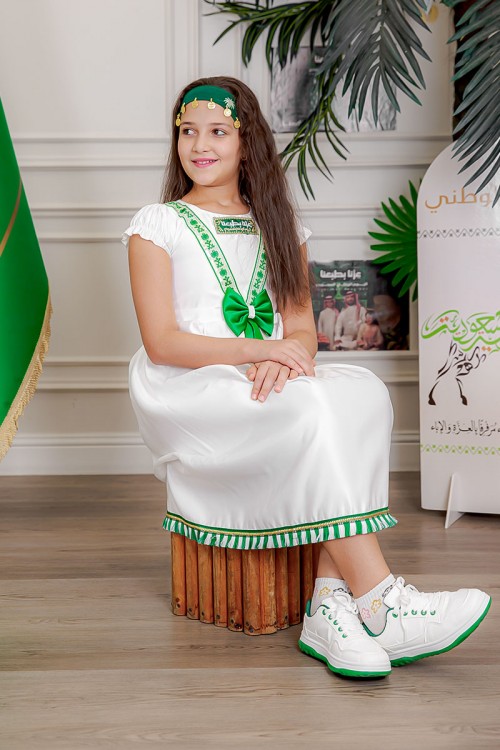 فستان بناتي لون أبيض مزين بتطريز اليوم الوطني ياقة دائرية بأكمام قصيرة و فيونكة من الأمام و رباط من الخلف