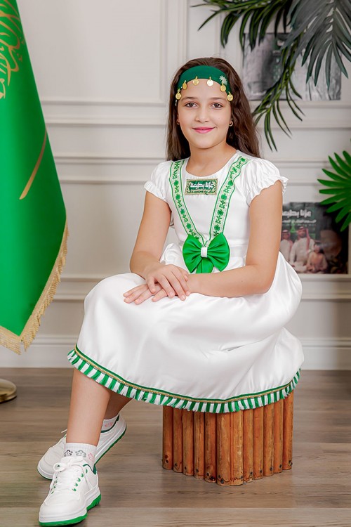 فستان بناتي لون أبيض مزين بتطريز اليوم الوطني ياقة دائرية بأكمام قصيرة و فيونكة من الأمام و رباط من الخلف