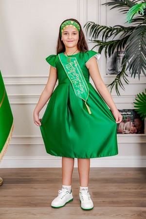 فستان بناتي لليوم الوطني لون أخضر مزين بوشاح من الأمام بتطريز عبارة المملكة العربية السعودية باللون الذهبي بأكمام قصيرة و رباط في الخلف مع تعليقة بشعار سيفين و نخلة 