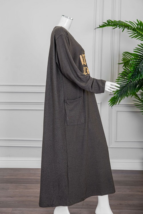 قميص نسائي شتوي طويل لون زيتي مزين بكتابات و رسومات من الأمام ياقة دائرية و جيوب من الجانبين و أكمام طويلة