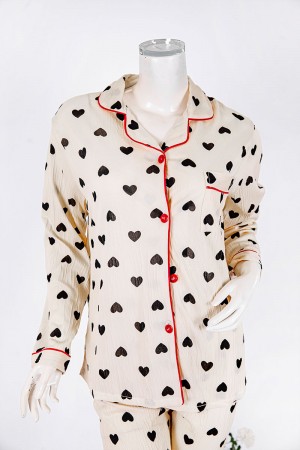 بجامة نسائية قطعتين لون بيج مزينة بقلوب باللون الأسود بلوزة بياقة مطوية و جيب و أزرار من الأمام بأكمام طويلة مع بنطلون طويل 