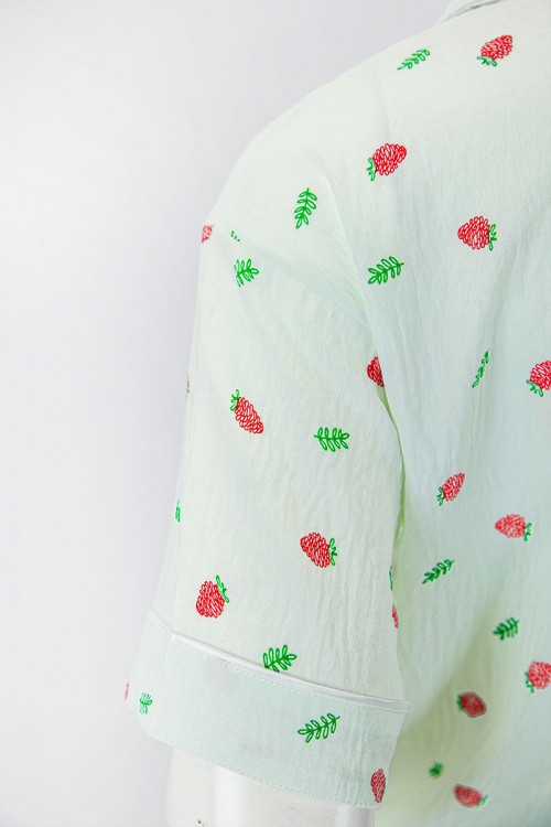 بجامة نسائية قطعتين لون تفاحي مزينة برسومات بلوزة بياقة مطوية و جيب و أزرار من الأمام بأكمام قصيرة مع بنطلون طويل