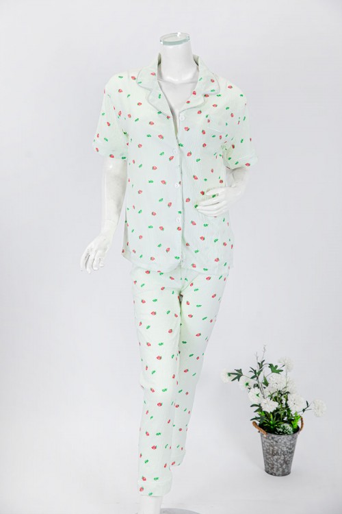 بجامة نسائية قطعتين لون تفاحي مزينة برسومات بلوزة بياقة مطوية و جيب و أزرار من الأمام بأكمام قصيرة مع بنطلون طويل