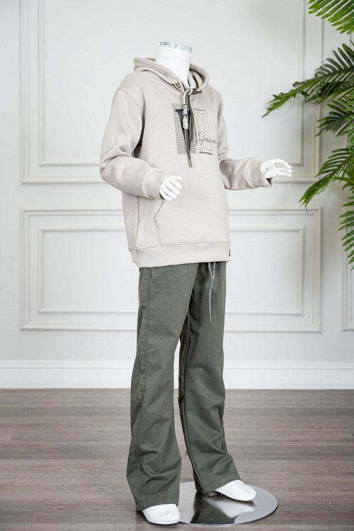 طقم قطعتين ولادي شتوي بلوزة لون بيج مزينة بكتابات من الأمام بقبعة متصلة برباط و بجيوب و أكمام طويلة و بنطلون طويل لون زيتي برباط في الخصر