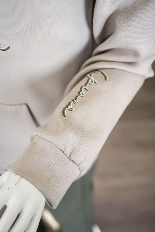 طقم قطعتين ولادي شتوي بلوزة لون بيج مزينة بكتابات من الأمام بقبعة متصلة برباط و بجيوب و أكمام طويلة و بنطلون طويل لون زيتي برباط في الخصر