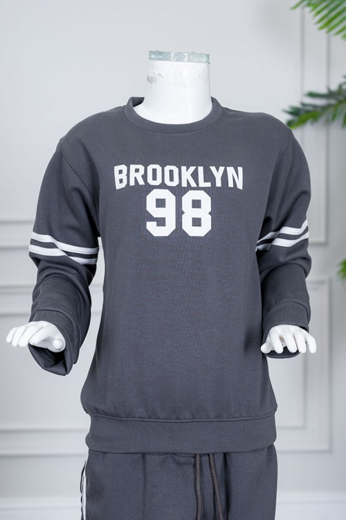 طقم بناتي شتوي قطعتين لون رصاصي بلوزة بياقة دائرية مزين بكتابات و خطوط باللون الأبيض بأكمام طويلة مع بنطلون طويل برباط في الخصر و جيوب من الجانبين