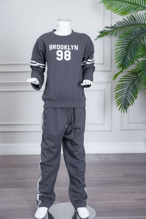 طقم بناتي شتوي قطعتين لون رصاصي بلوزة بياقة دائرية مزين بكتابات و خطوط باللون الأبيض بأكمام طويلة مع بنطلون طويل برباط في الخصر و جيوب من الجانبين 