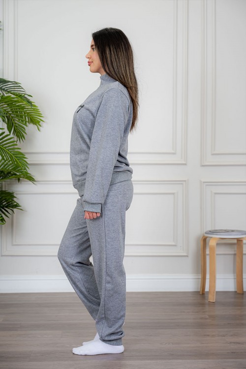 بيجاما نسائية قطعتين لون رمادي مزينة بكتابات من الأمام ياقة عالية بسحاب و بأكمام طويلة مع بنطلون طويل برباط في الخصر