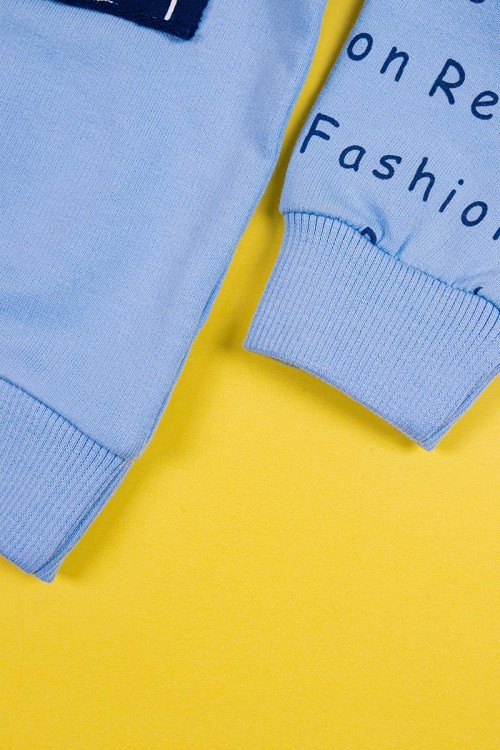 طقم قطعتين ولادي بلوزة لون سماوي مزينة بكتابات من الأمام و الخلف و بأكمام طويلة مع بنطلون كحلي طويل برباط في الخصر و زم في الأطراف