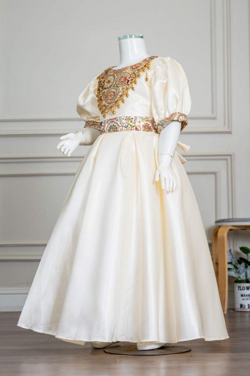 فستان بناتي طويل لون بيج فاتح مزين بتطريز ملون من الياقة و أطراف الأكمام و بحزام في الخصر